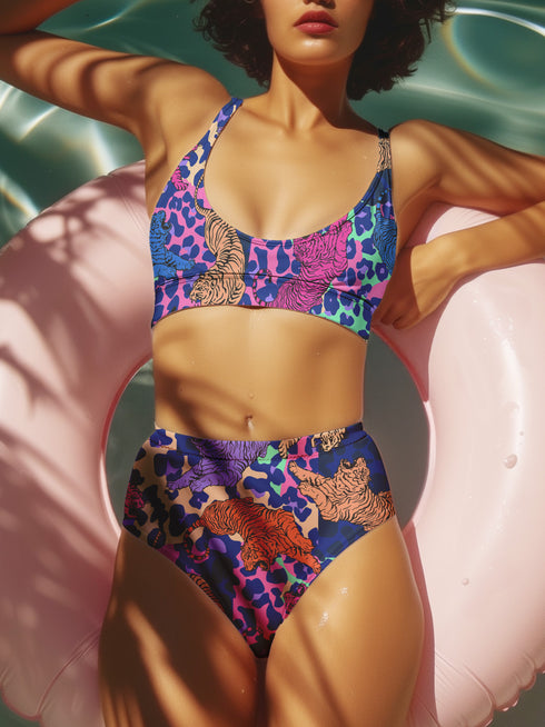 Psychedelic animal print bikini top with multicolor tiger pattern in neon pink, purple, orange, and blue, made of stretchy recycled fabric with wide shoulder straps and scoop neckline.